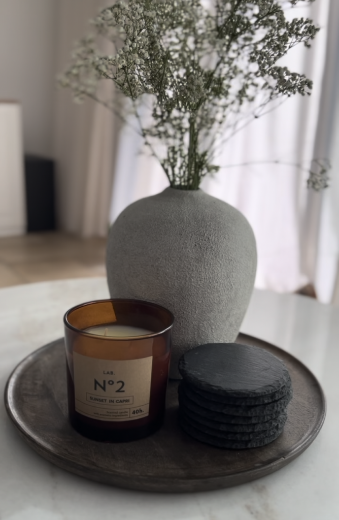 Dekotablett mit Vase, Kerze und Untersetzern.