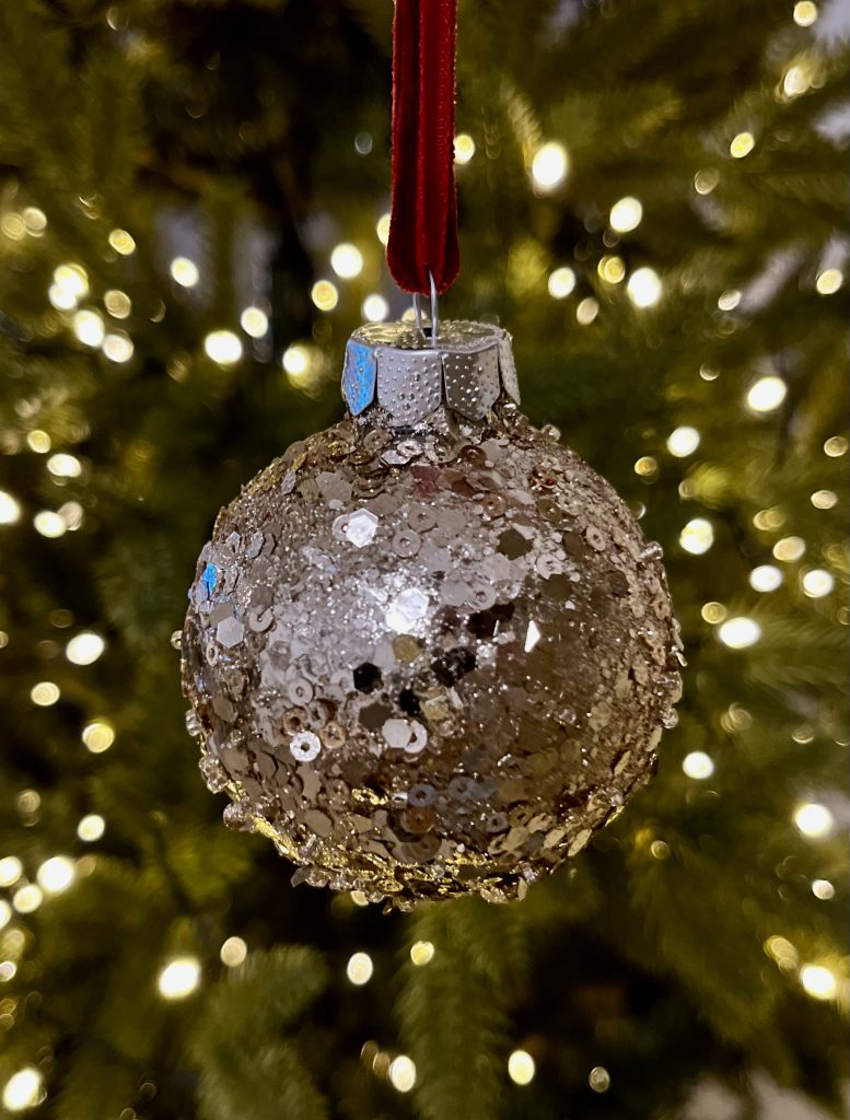 DIY Glitzer Christbaumkugel in gold hängt am Baum.